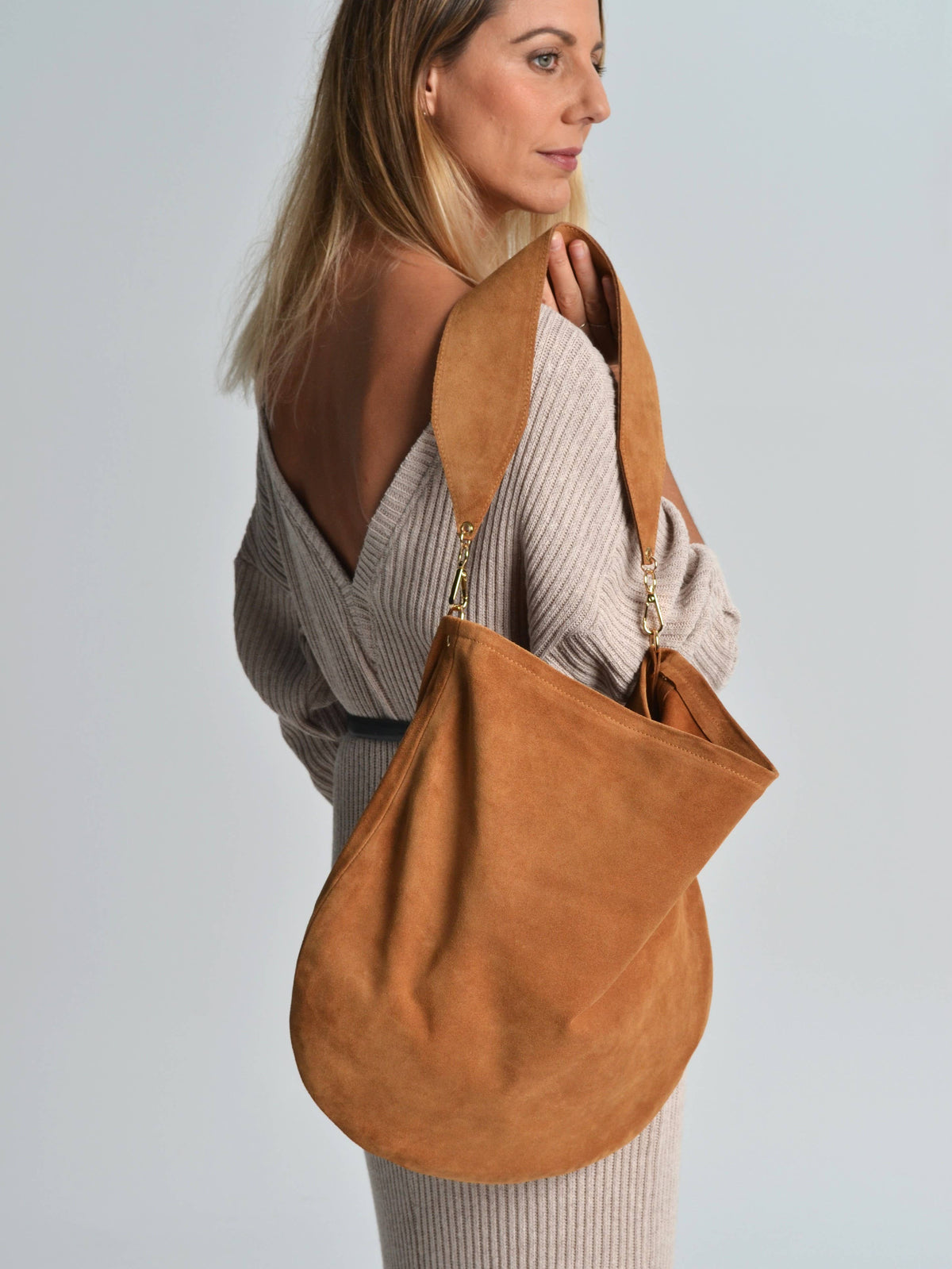 Woman carrying a brown leather handbag against a plain background